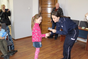 Policjantka wręcza dziewczynce grę &quot;Piotruś&quot; o bezpieczeństwie.