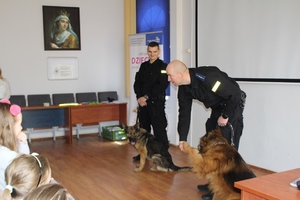 Pies Cwaniak podaje łape policjantowi.