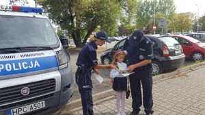 Policjanci wręczają dziewczynce odblaski.