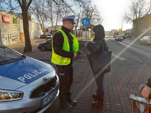 Policjant rozmawia z pieszą o zasadach ruchu drogowego