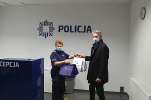 Policjantka przekazuje paczki z nagrodami nauczycielowi szkoły z Kruszwicy